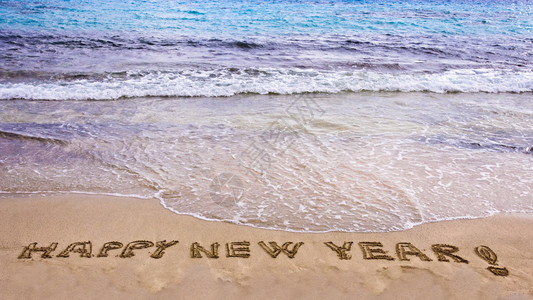 新年快乐在沙中写下欢欣的新年和感叹点背景图片