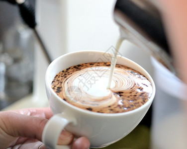 咖啡师研究牛奶制作拿铁艺术图片