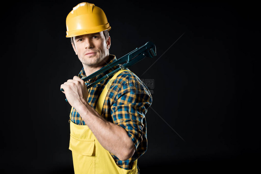 自信的男工人拿着钢管扳手看着在黑色上图片