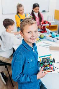 男孩在课堂上带着微笑的男孩拿着机器人图片