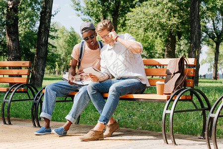 坐在长椅上并一起在公园学习的多文化背景图片
