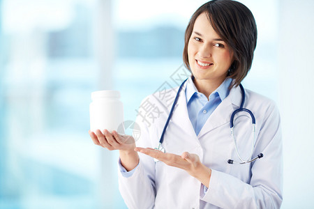 一个微笑着的药剂师拿着一瓶药丸指图片