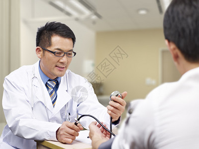 测量病人血压的亚洲医生图片