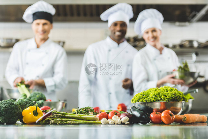 餐饮厨房中微笑着的多文化厨师前面图片