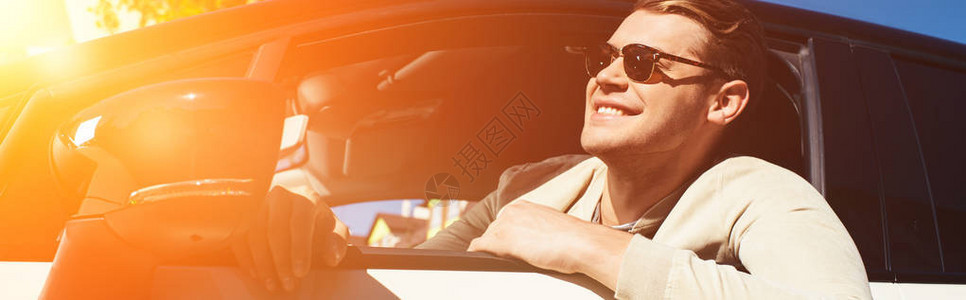 微笑着的年轻男子从汽车驾驶车背景图片