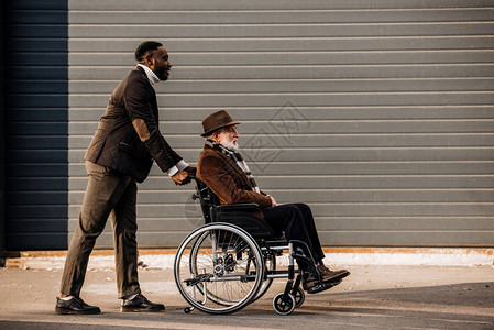 坐在轮椅上的老年残疾男子和在街上骑车的非图片