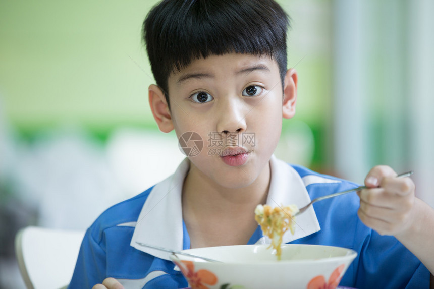 坐在家里吃饭的年轻亚裔男孩图片