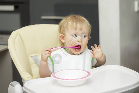 小孩用餐盘里的勺子吃饭图片