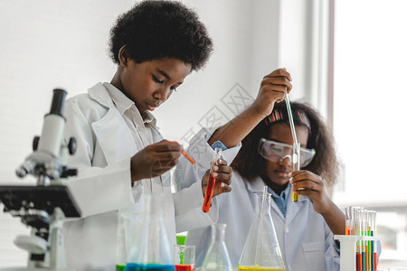 两个非洲裔美国可爱的小男孩和女孩在桌上的科学课上学习研究和做化学实验图片