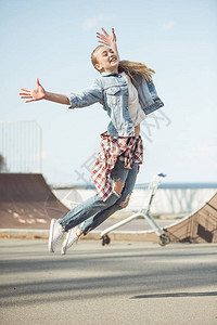时髦的少女在滑板公园跳跃图片
