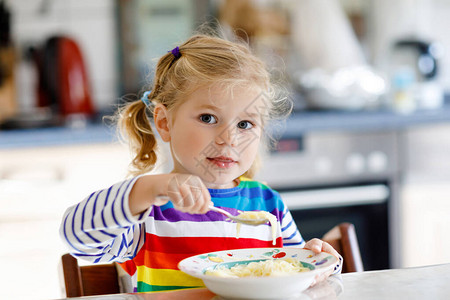 可爱的蹒跚学步的女孩午餐吃健康的鸡肉面条汤可爱的快乐婴儿在家或托儿所日托或幼儿园吃东西背景图片
