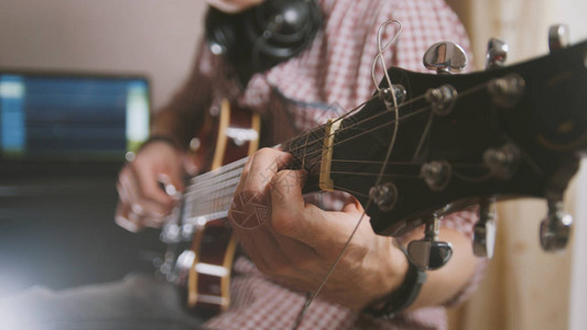 男音乐家弹吉他手拉紧专注于吉他壁图片
