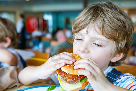 可爱的健康学龄前儿童男孩坐在学校或托儿所咖啡馆吃汉堡包快乐的孩子在餐厅吃健康的有机和素食品童背景图片