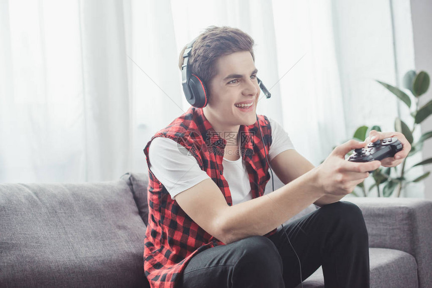 快乐的少年用耳机玩电游戏在图片