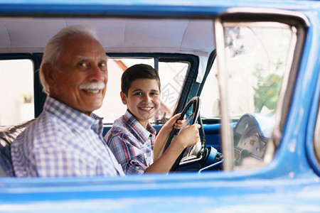 家庭和代沟老爷和孙子在一起他教开车这个男孩拿着一辆60年代的老爷车的volante他们都笑得很开背景图片