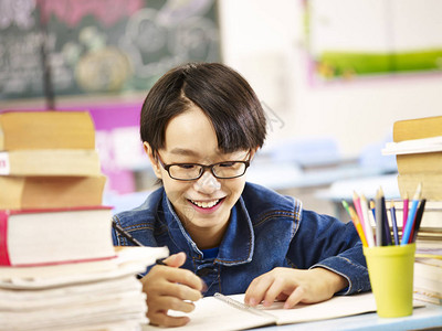 快乐的亚洲小学生男孩在课堂上学习微笑图片