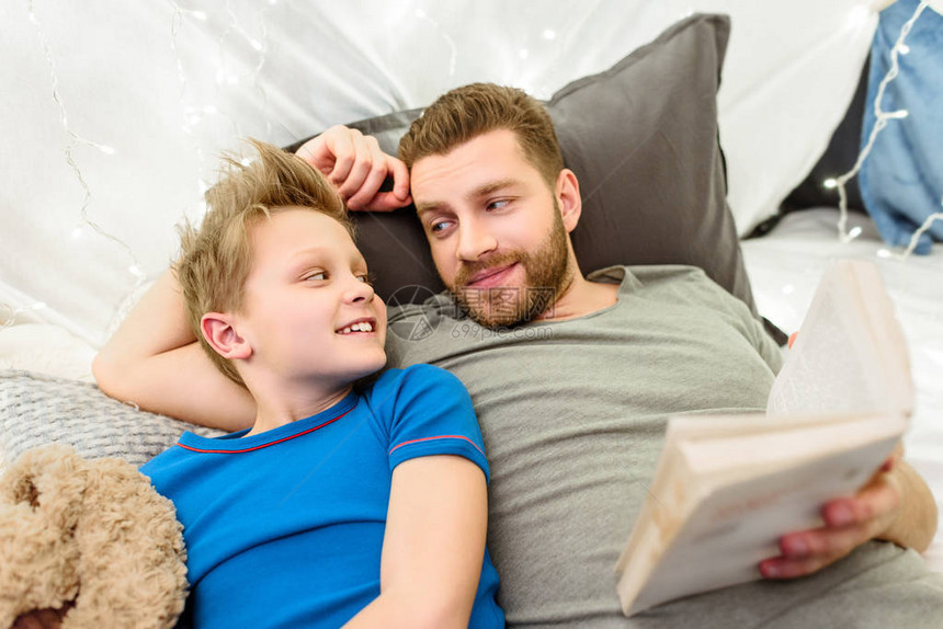 快乐的父亲和儿子躺在书本图片
