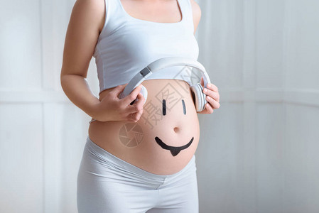 怀孕妇女肚子上戴耳机家里有微笑符号的孕妇图片