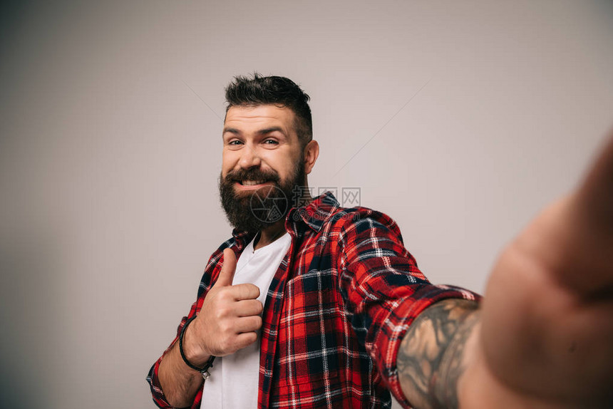 穿着格斗衬衫的笑着长胡子的男人在拿自拍时大图片