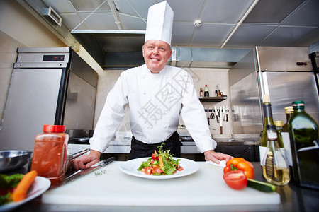 男厨师在餐厅厨房烹饪蔬菜图片