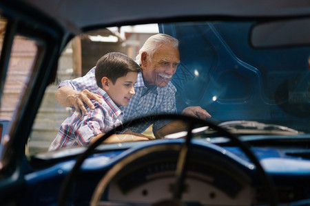 家庭和代沟老爷和孙子在一起这位老人展示了一辆从60年代到十几岁的孩子的老爷车的引擎他们笑得很开心背景图片