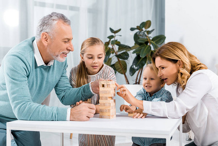 快乐的祖父母和孙辈在家里一起玩木塔游戏图片