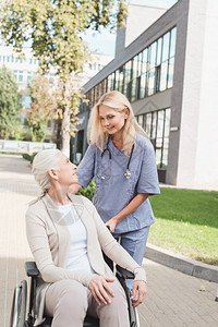 微笑的护士和坐在轮椅上的残疾老年妇女在疗养图片