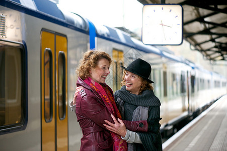 两个朋友在户外火车站平台上互打招呼时笑图片