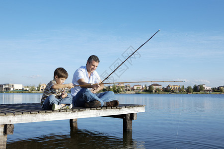 快乐的父子在木码头钓鱼图片