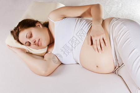 孕妇睡觉和触摸她的肚子图片