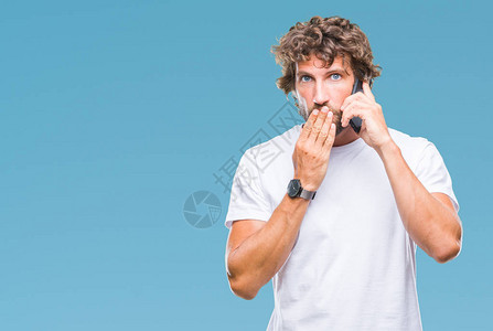 英俊的西班牙裔男子模特在孤立的背景下用智能手机说话图片