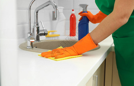 身着防护手套的妇女清洁厨房水槽图片