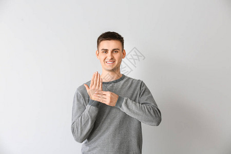在浅色背景下使用手语的年轻聋哑人图片