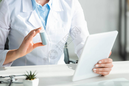 医生在办公室数字平板电脑网上咨询时向病人展示药片的图片