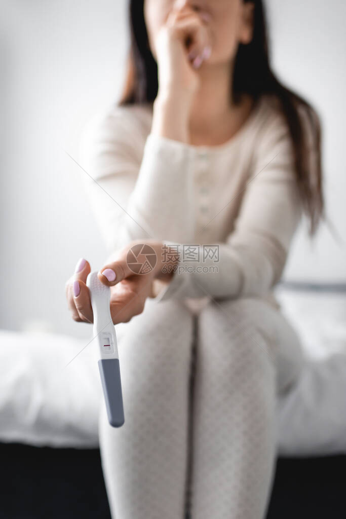 妇女坐在床上和进行孕检结果为负结果的怀孕检图片