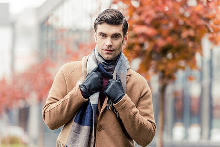 穿着大衣皮手套和围巾的帅男子在秋天图片