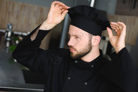 在餐厅厨房戴帽子的英俊厨师图片