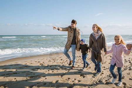 父母牵着孩子的手在海边散步父亲图片