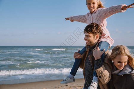 秋天一家人带着快乐的女儿在海边散步图片