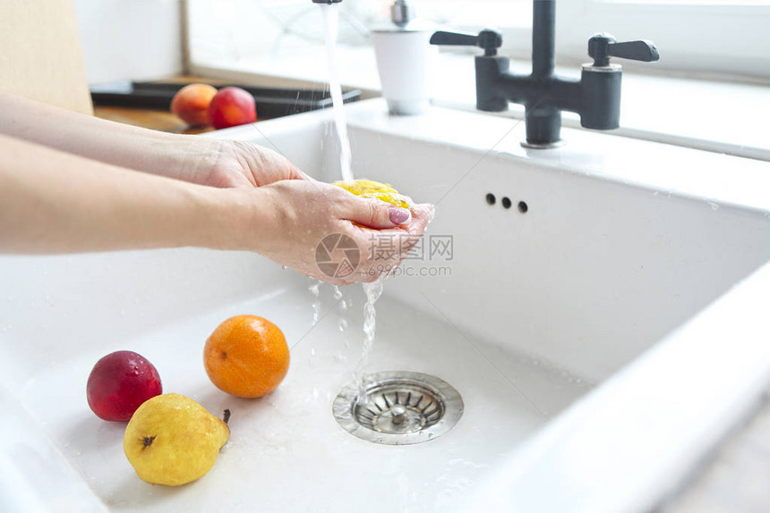 女人在水槽的厨房里洗水果特写图片
