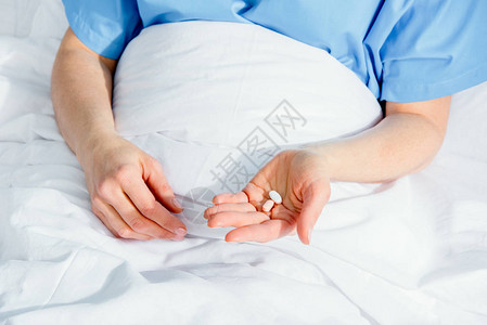 躺在病床上的女人手里拿着药丸图片