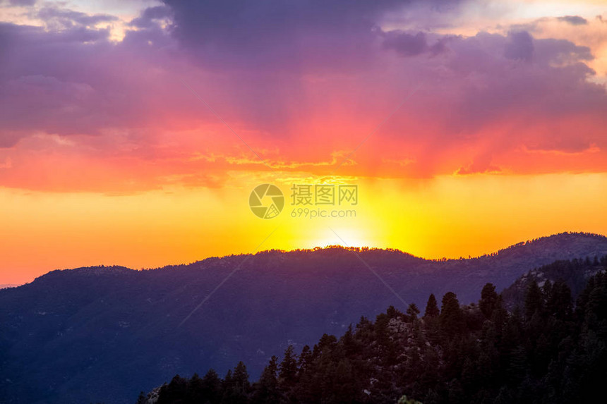 在山脉的五颜六色的日落与明亮的紫色和黄色的天空图片