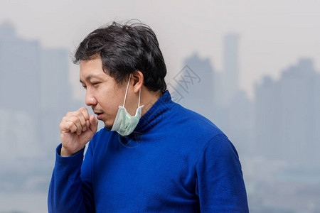 戴面罩对抗空气污染的亚洲男子在HighApartment的阳台上咳嗽图片