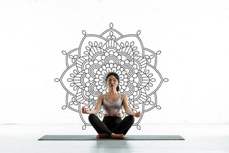 平和的泰女在瑜伽垫上做瑜伽在曼达拉白图片