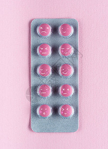 粉红色吸塑包装中带有滑稽面孔的药物的顶部视图图片