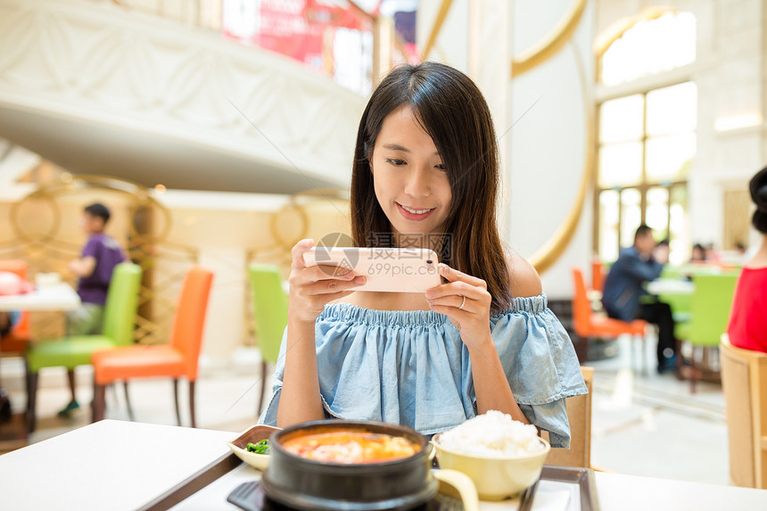 在餐厅的手机拍照的女人图片