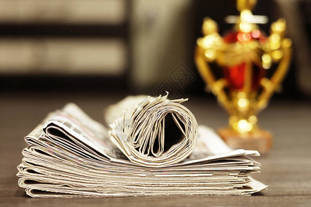 一堆报纸和金奖杯感觉赢家的概念折叠和卷起的小报期刊图片