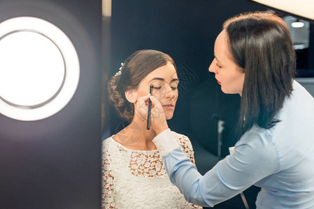 在美容工作室模特脸部应用眼影的焦点化妆艺术图片
