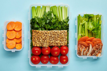 以蓝色隔离的新鲜健康蔬菜饼干和肉类为主的食品容器安图片