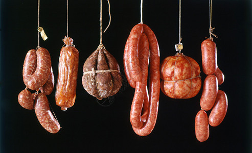 各种意大利新鲜香辣肠的组合在黑色下在屠宰场上挂出来治病背景图片